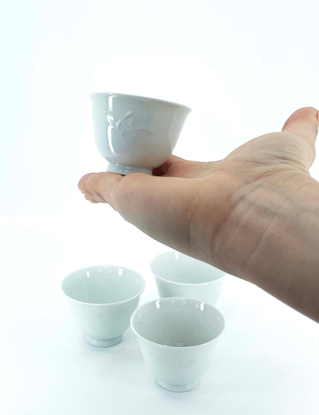 Pale blue porcelain ochoko cups with a delicate embossed flower design.